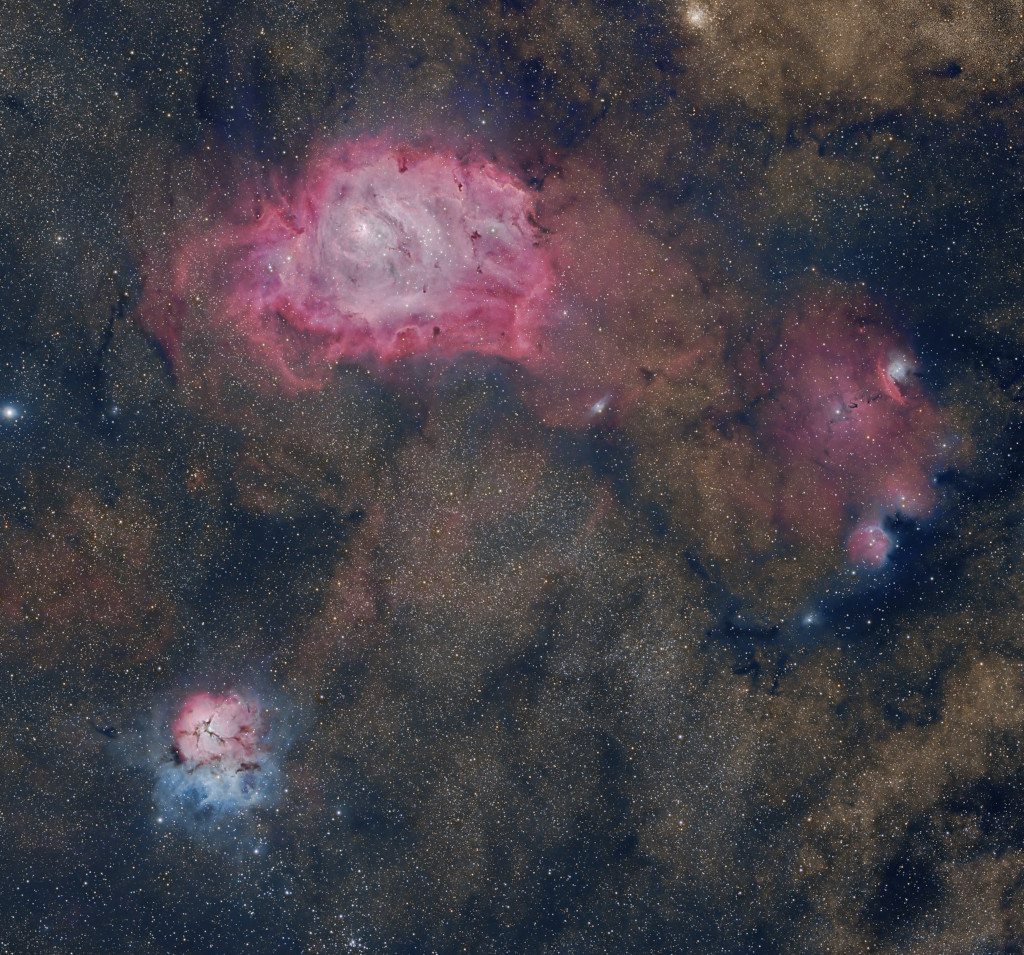 Drei Nebel sind zwischen dichten Sternfeldern und Dunkelnebeln verteilt: Links oben der Lagunennebel, links unten der Trifidnebel und rechts NGC 6559.