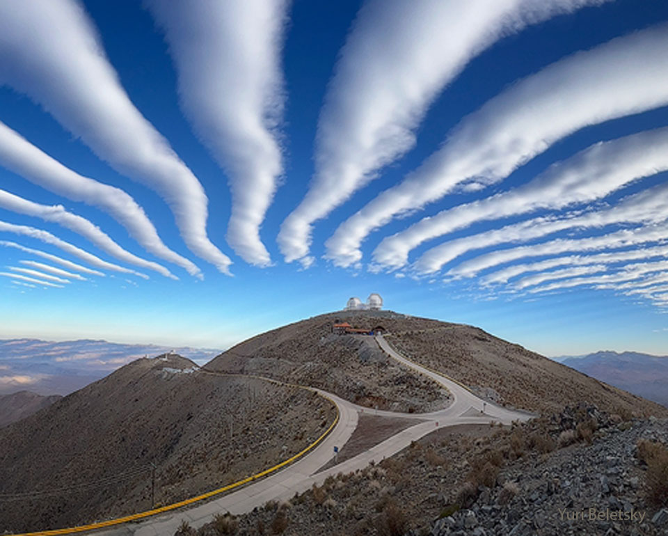 Am blauen Himmel verlaufen walzenförmige Wolken, die scheinbar über dem Hügel des Las-Campanas-Observatoriums zusammen.