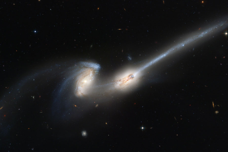 In der Mitte des dunklen bildes sind zwei Galaxien mit großen hellen Kernen, eine davon hat einen rudimentären Spiralarm, die andere hat einen lang gezogenen Schweif, der nach rechts oben reicht.