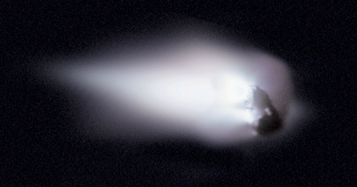 Rechts ist der Kern des Kometen Hally, sein großer, weiß leuchtender Schweif breitet sich nach links aus.