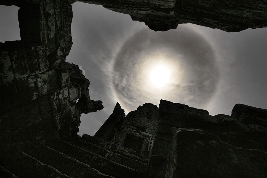 Über den Silhouetten von antiken Gebäuden leuchtet am Himmel die Sonne, umgeben von einem strahlenden Ring.