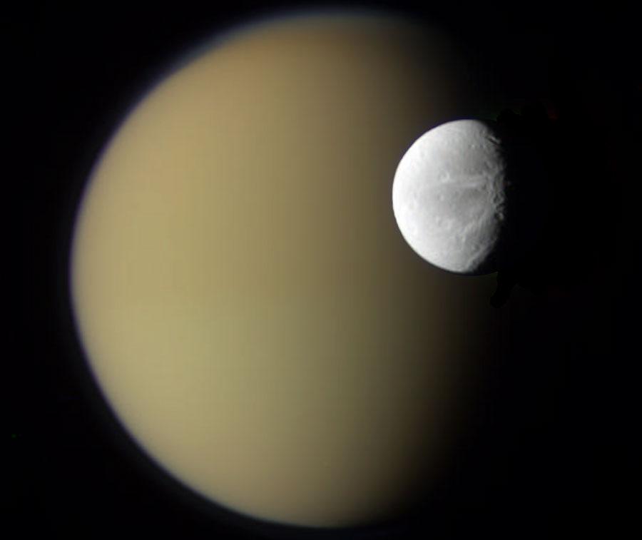 Hinter einem grauen Mond mit Kratern und Schlieren befindet sich ein ockerfarbener Mond. Beide Monde sind von links beleuchtet.