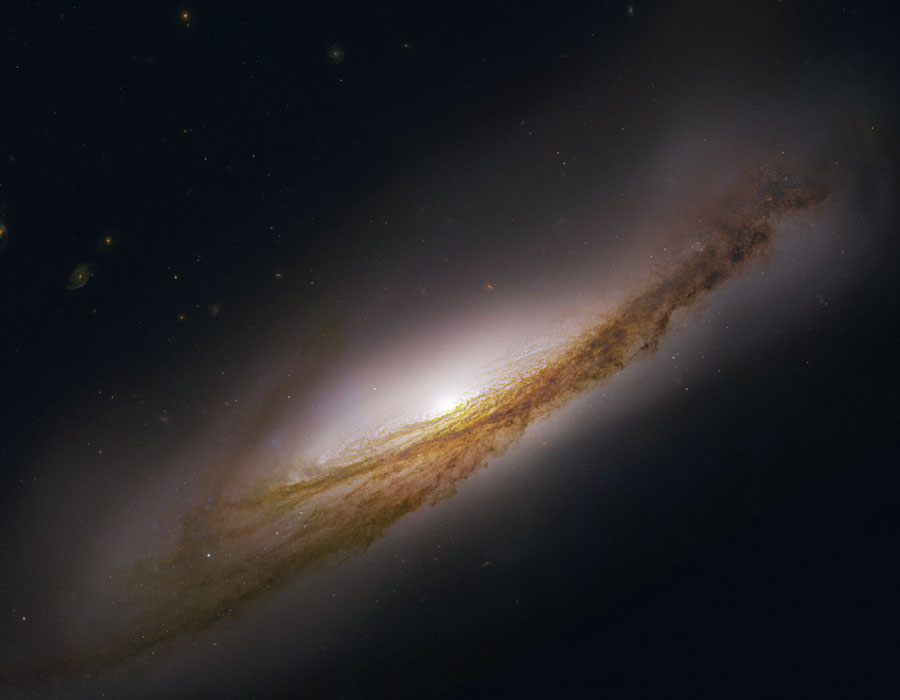 Im Bild ist eine Spiralgalaxie mit sehr markanten Staubbahnen schräg von oben sichtbar, sie wirkt verkrümmt.