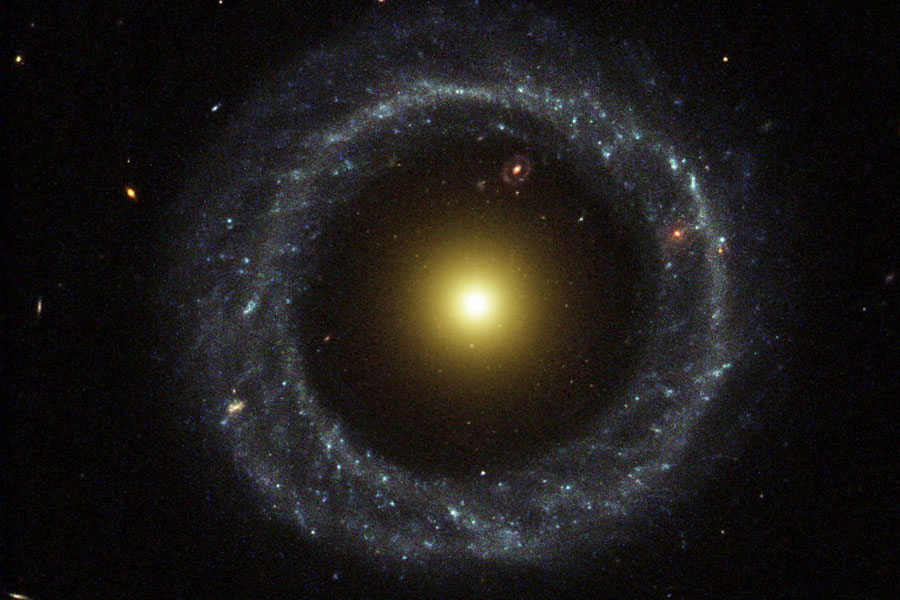 In der Mitte leuchtet ein helles, diffuses rundes Objekt, außen herum verläuft ein Ring aus blauen Sternen, dazwischen ist eine Lücke.
