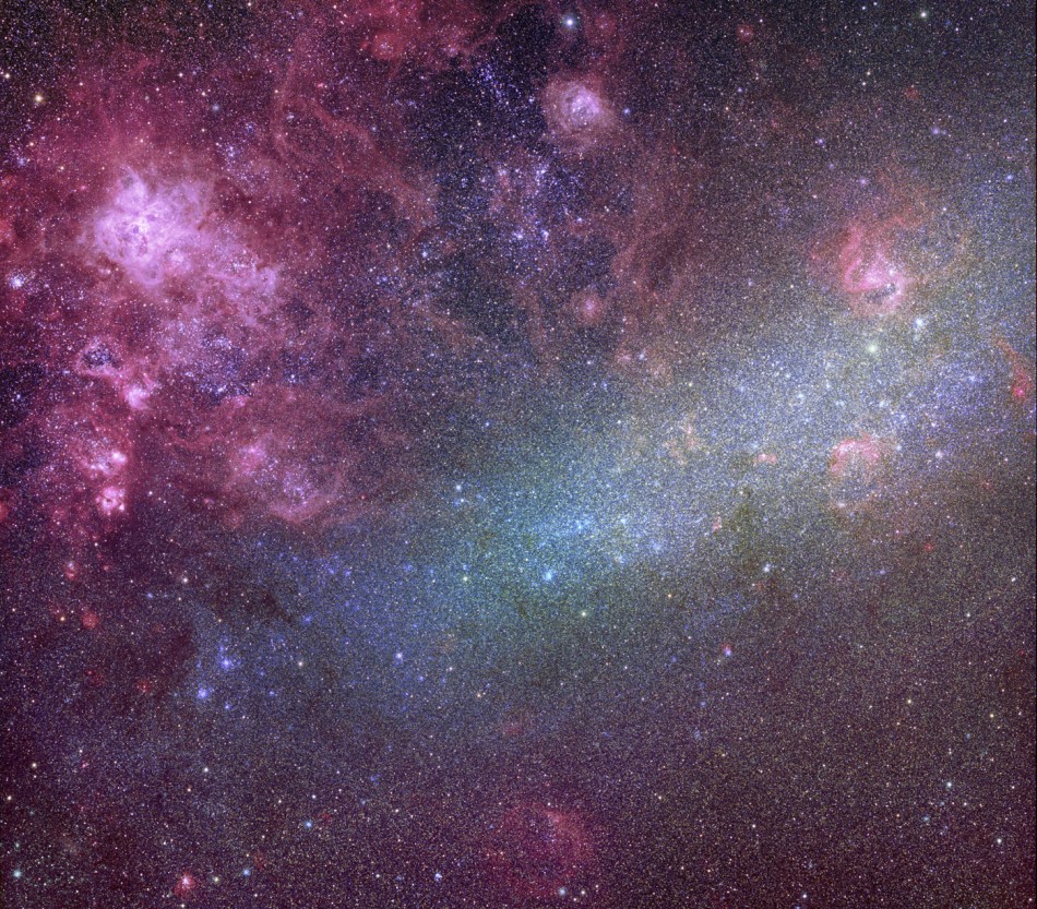 Der Balken der GMW mit vielen Sternen verläuft diagonal durchs Bild. Links oben ist eine riesige rosarote Nebellandschaft, der Tarantelnebel.