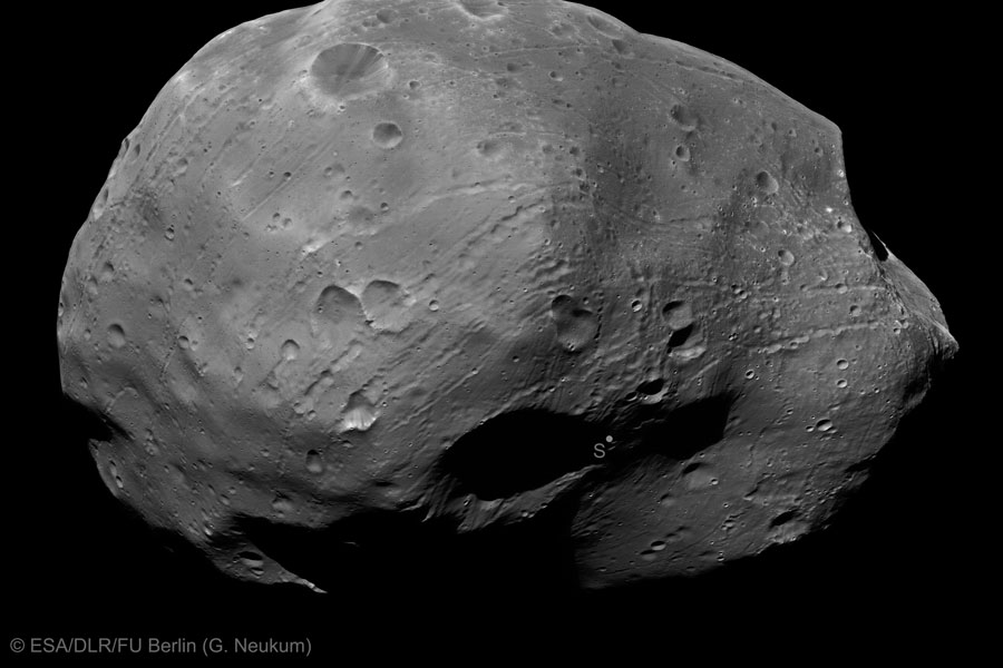 Der Mond Phobos ist schwarzweiß abgebildet. Er ist von Kratern und feinen Rillen übersät und erinnert an eine unförmige Kartoffel.