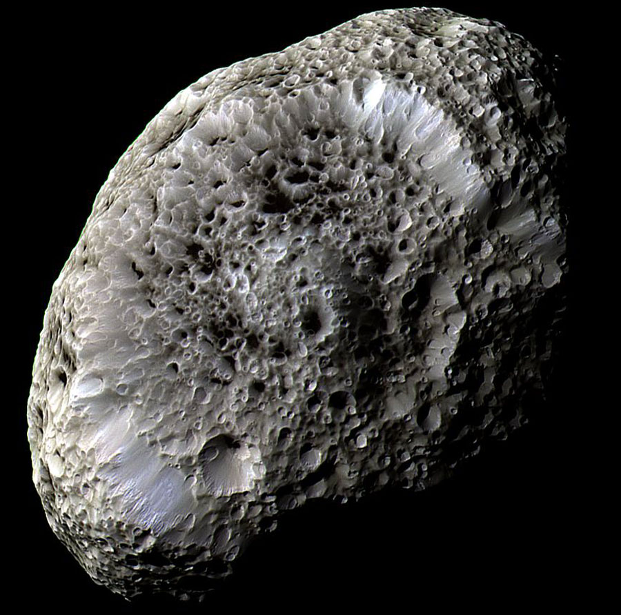 Bildfüllend ist ein Objekt zu sehen, das an einen Badeschwamm erinnert. Es ist rund und grau und von unhähligen Kratern übersät.