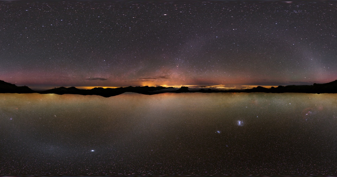 Zwei Panoramen zeigen die ganze Milchstraße. In der Mitte laufen die Horizonte beider Bilder zusammen. Oben ist auch das Licht von Städten zu sehen, unten die Magellanschen Wolken.