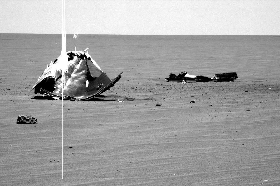 Im Bild ist links ein großer Teil vom Hitzeschild des Rovers, darunter - davor - liegt ein seltsam geformter Stein, es ist ein Meteorit.