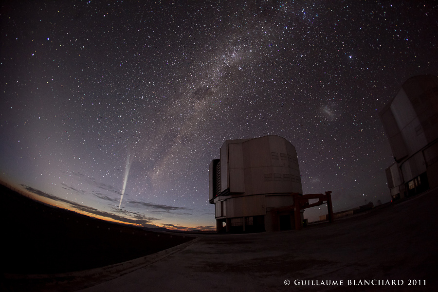 Als Silhouette steht ein Teleskop der VLT vor dem Horizont, über dem noch ein Streifen Abenddämmerung leuchtet. Oben steigt die Milchstraße steil am Himmel auf, vom Horizont steigt der Schweif des Kometen Lovejoy (C/2011 W3) auf.