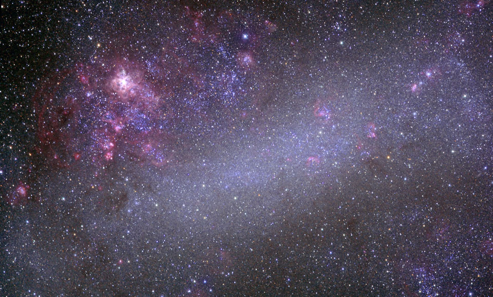 Mitten im Bild leuchtet eine digitale nebelige Sternwolke, rundherum sind kleine violette Nebel verteilt, links oben ist ein violetter Nebel mit hellem Zentrum.