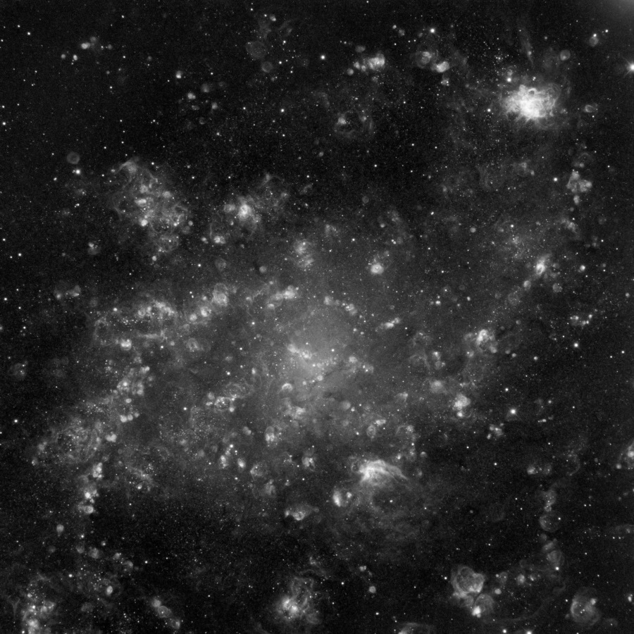 Die Galaxie im Bild wirkt sehr wolkig, es sind keine Spiralarme erkennbar. Das Bild ist schwarzweiß.