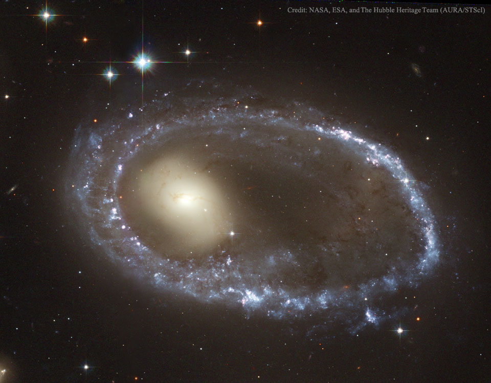 Die abgebildeete Galaxie besteht aus einem hellgelben, diffus verschwommenem Zentrum, das von einem ovalen, exzentrischen Ring aus blauen Sternen und Sternbildungsgebieten umgeben ist.