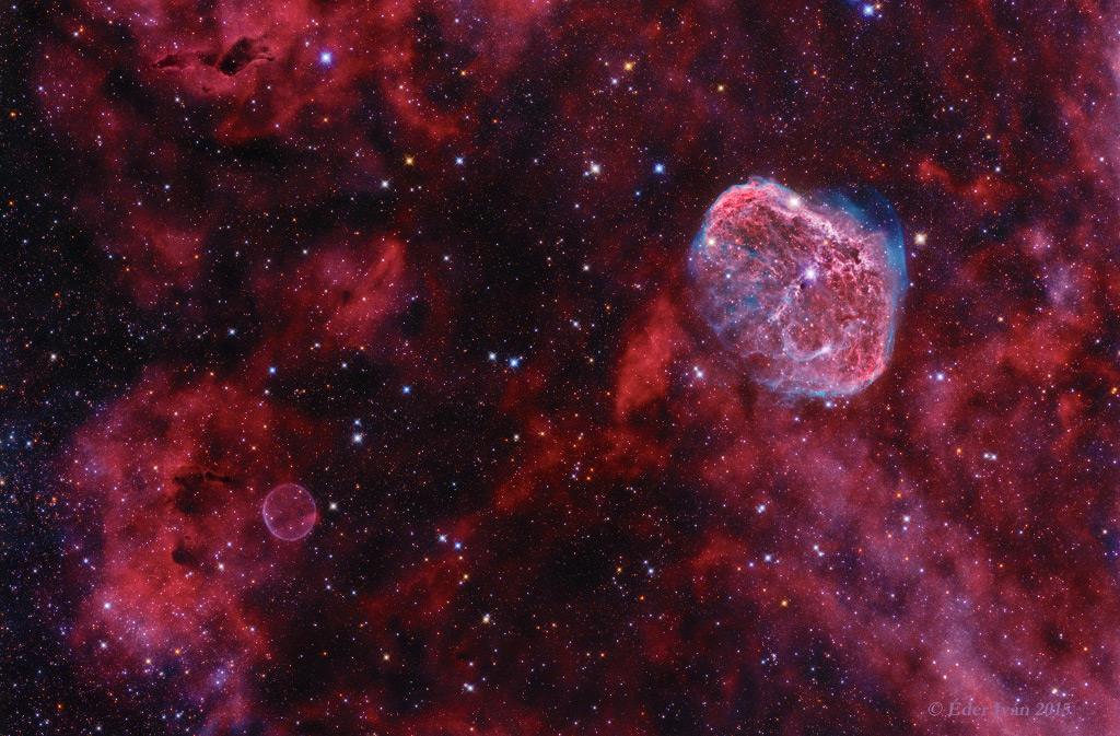 Das Bild ist relativ gleichförmig mit magentafarbenen Nebeln und wenigen Sternen gefüllt. Links unten leuchtet zart ein seifenblasenförmiger Nebel, rechts oben der helle, stark strukturierte Sichelnebel.