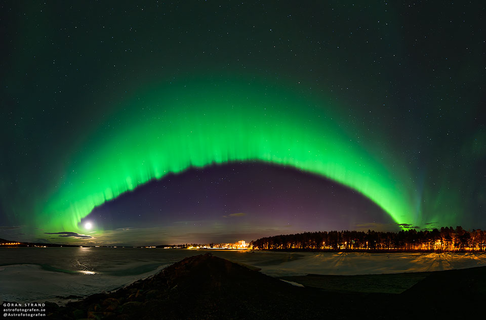 Am sternklaren Himmel wölbt sich ein grünes bogenförmiges Polarlicht.