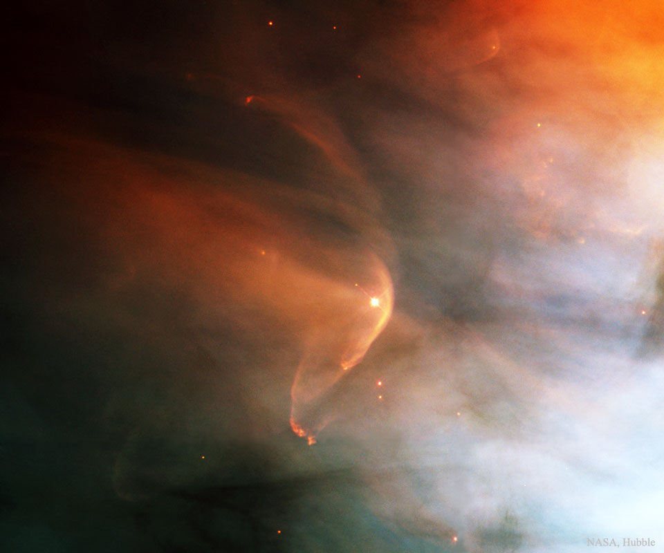Mitten in einem Nebel leuchtet ein Stern, der rechts von einer Bugwelle umgeben ist.