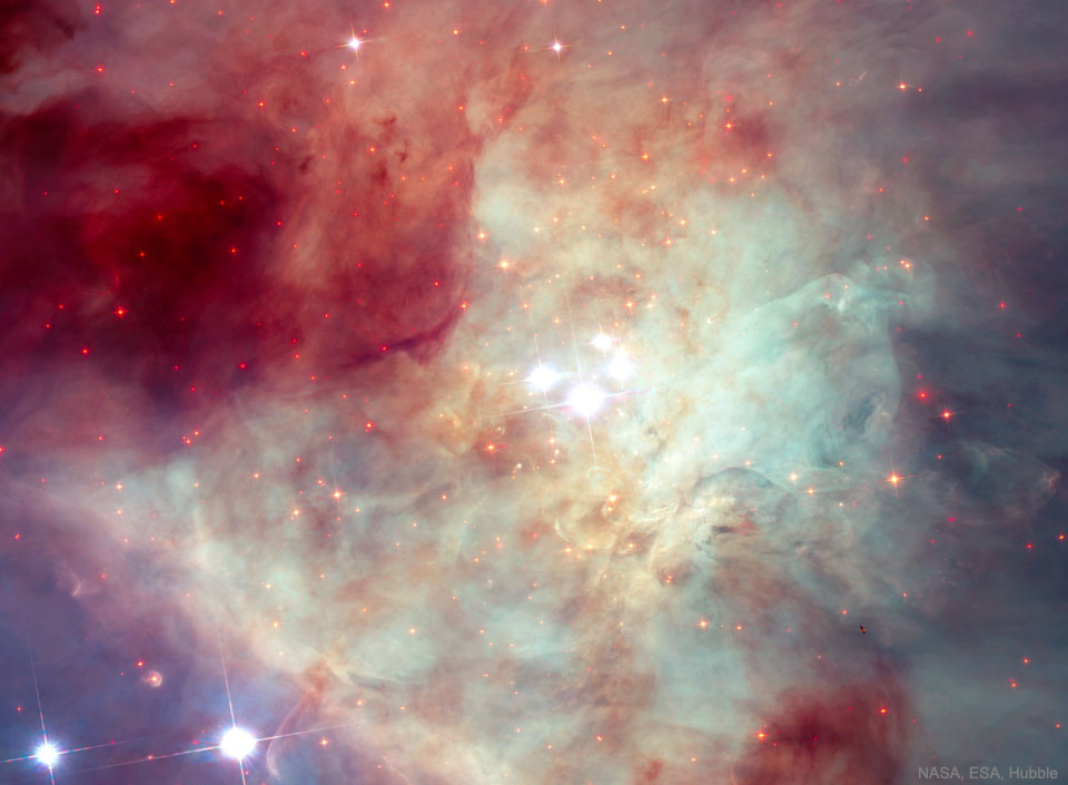 Das Bild ist von Nebeln gefüllt, in der Mitte leuchten die vier markanten Sterne des Trapeziums im Orionnebel, kaum vom hellen Hintergrund zu unterscheiden. Links oben ist ein großer dunkelroter Nebelbereich, links unten ein kleinerer, violetter Nebelteil mit zwei Sternen.