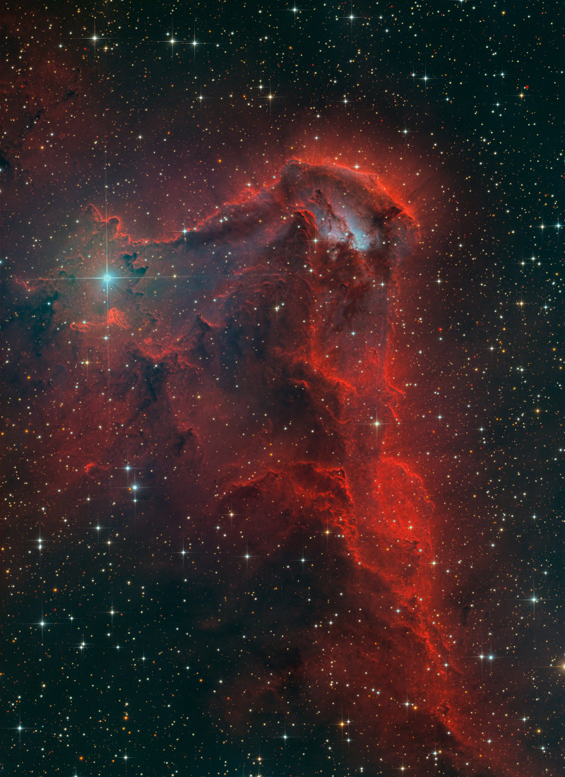 Hinter lose verteilten blau leuchtenden Sternen türmt sich ein rotes Staubgebirge auf. Es ist die Emissionsregion RCW 85.