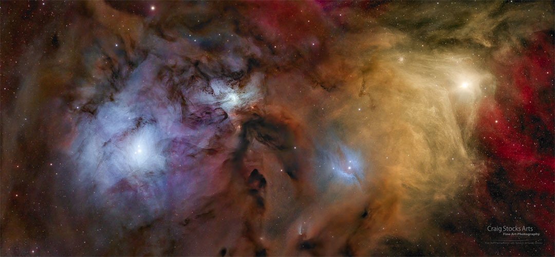 Bunte Nebel und Sterne füllen das weite Bild. Links ist der gelbe Stern Antares zu sehen und blaue Reflexionsnebel umgeben einen zentralen Nebel und den Nebel rechts um das Sternsystem Rho Ophiuchi.