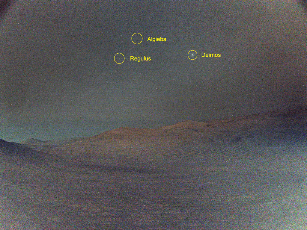 Über einer Marslandschaft geht der Mond Deimos auf. Er steht bei den hellen Sternen Regulus und Algieba.