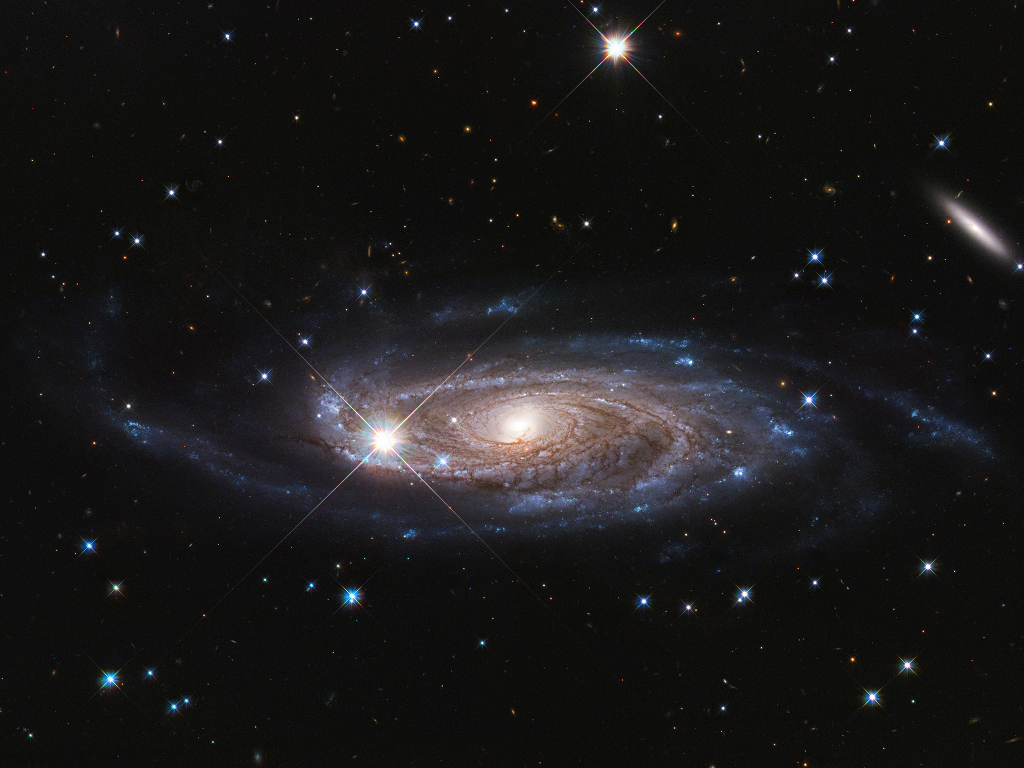 Die Galaxie im Bild ist gewaltig groß. Sie ist 8 Mal so breit wie die Milchstraße und enthält 10 Mal so viele Sterne. Ihre Rotation ist nur mit Dunkler Materie erklärbar.