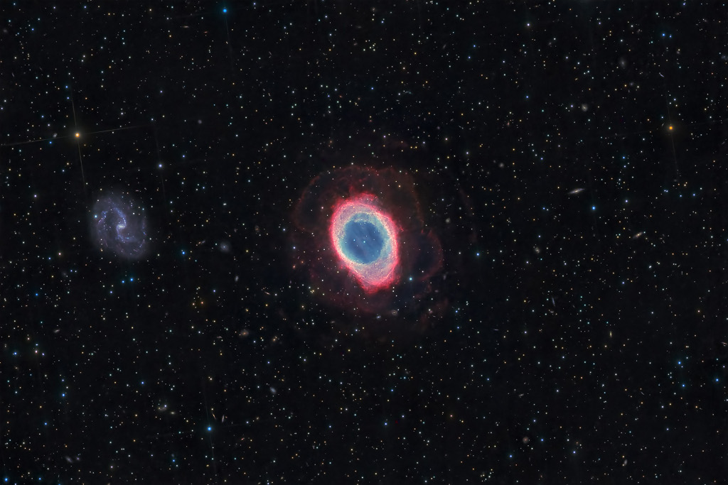 Mitten im Bild ist der bunte Ring M57, er leuchtet außen rot und innen gelb und blau. Links ist eine sehr blasse Spiralgalaxie, die scheinbar gleich groß ist wie M57.