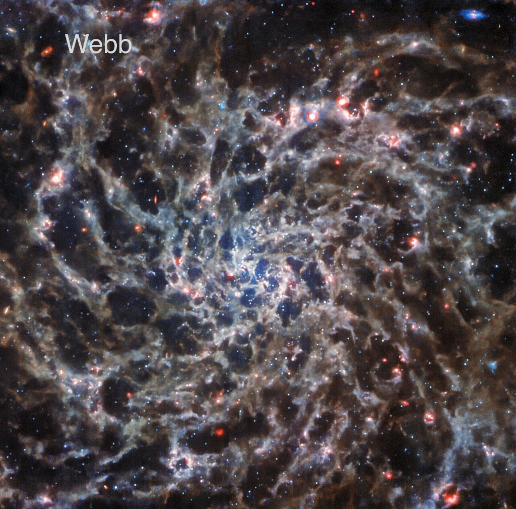 Die Galaxie IC 5332 wurde vom Weltraumteleskop James Webb abgebildet. Das Bild ist von einer alternativen Ansicht in sichtbarem Licht überlagert. Man sieht sie, wenn man den Mauspfeil über das Bild schiebt. (Smartphones: Link im Text)