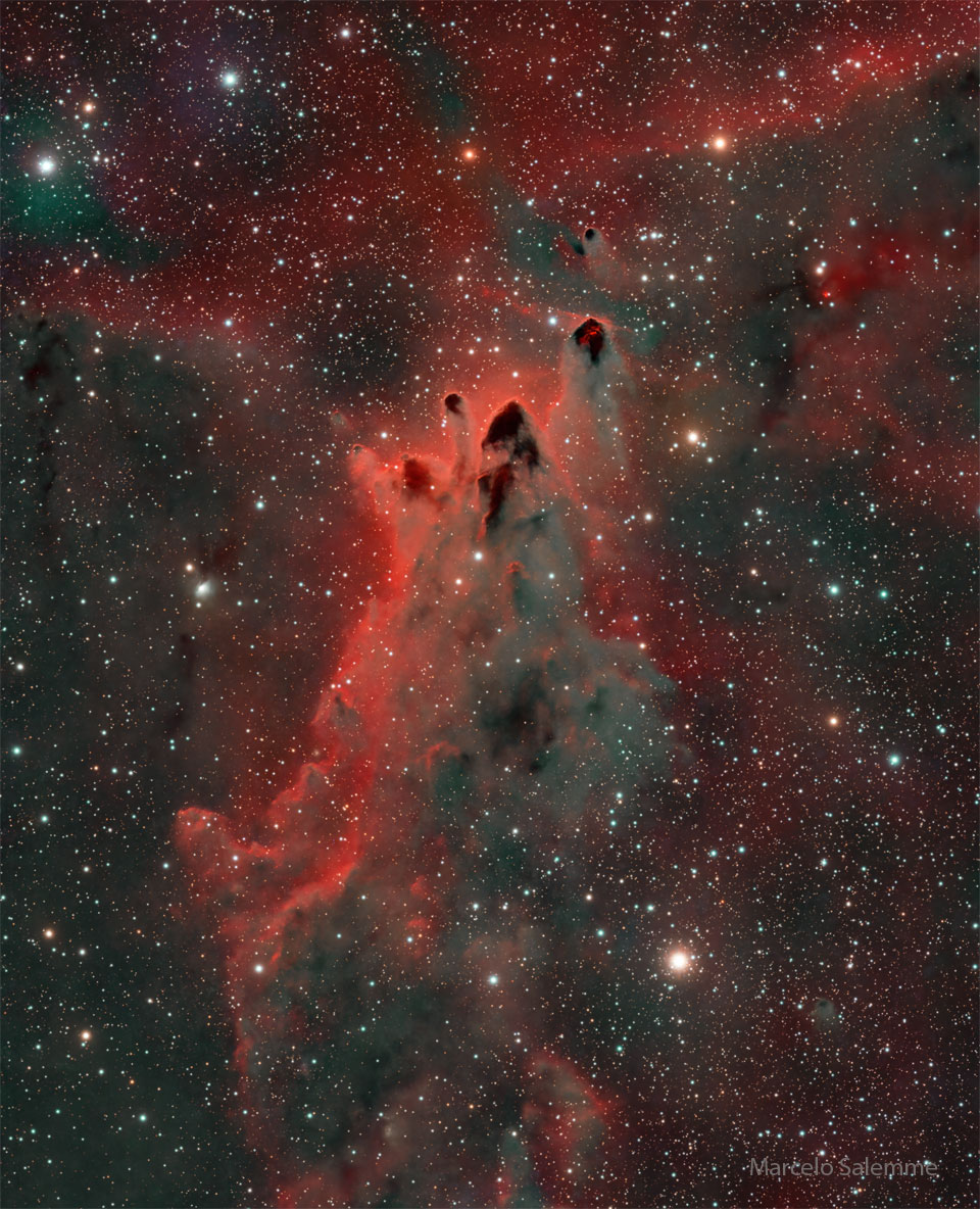 Diese dunklen Globulen aus Staub strömen vom Vela-Supernovaüberrest fort. Sie sind dunkel und von rot leuchtendem Gas umgeben. Der Hintergrund ist von Sternen gesprenkelt.